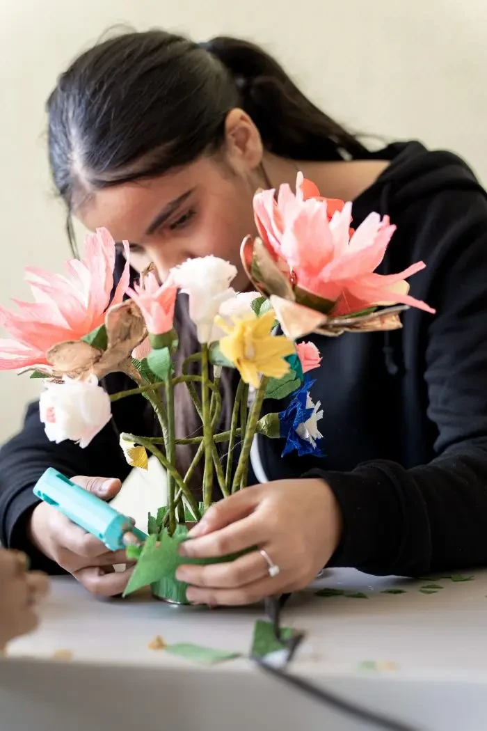 Jeune fille manipulant un bouquet de fleurs en papier lors d’un atelier manuel pour les Trophées bretons des transitions