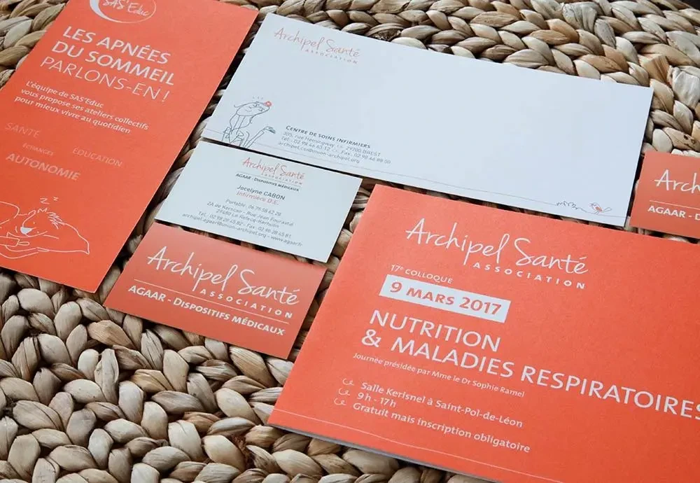 Photographie de supports de communication imprimés d’Archipel Santé, comprenant brochures, cartes de visite et documents d'information, disposés sur un tapis en fibres naturelles.