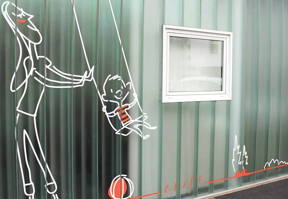 Fresque illustrée sur un mur extérieur vert, représentant un adulte poussant un enfant sur une balançoire, à côté d’une fenêtre, avec des éléments graphiques stylisés.