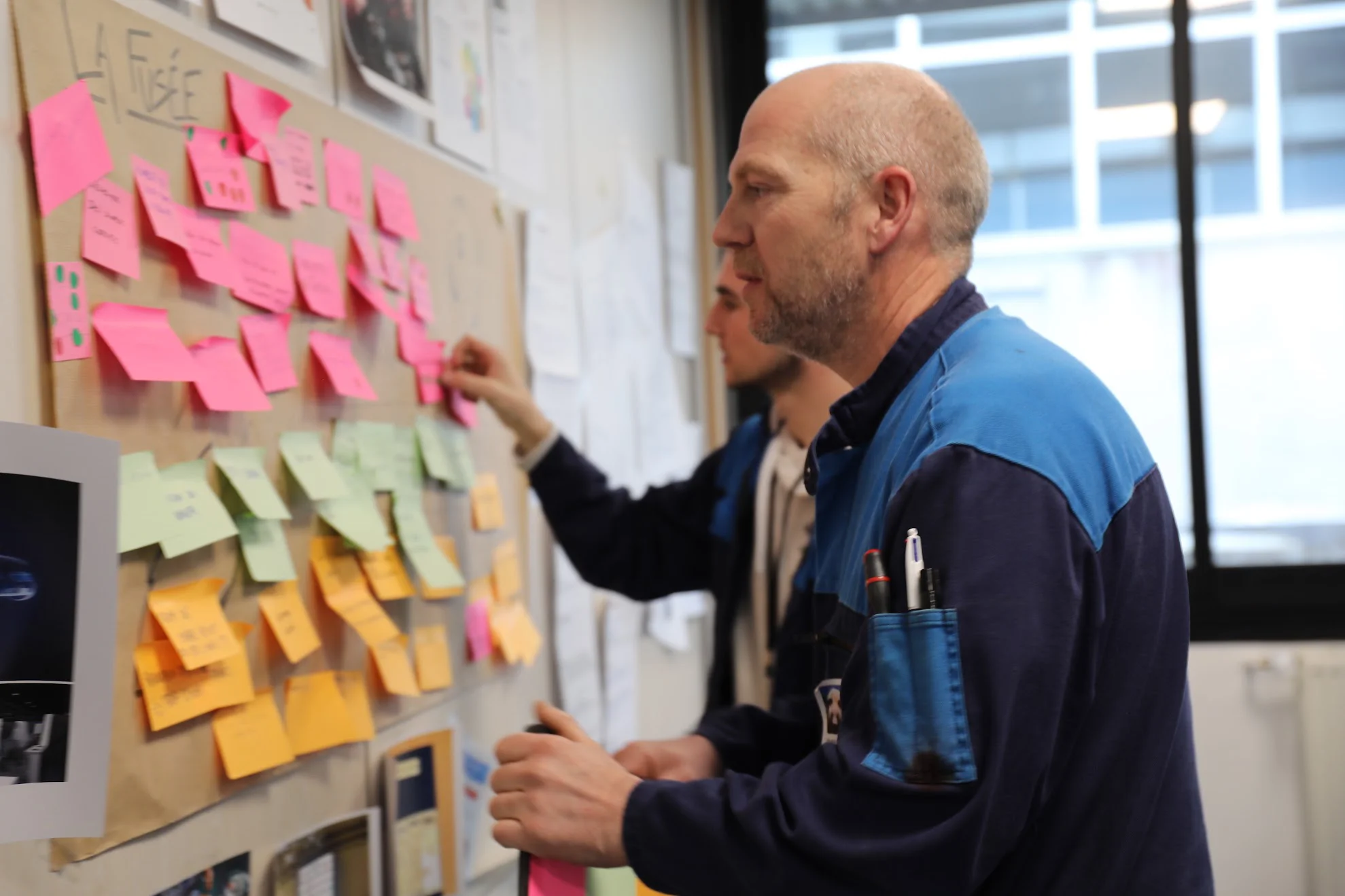 Homme devant panneau constellé de post-its lors d'un atelier de créativité