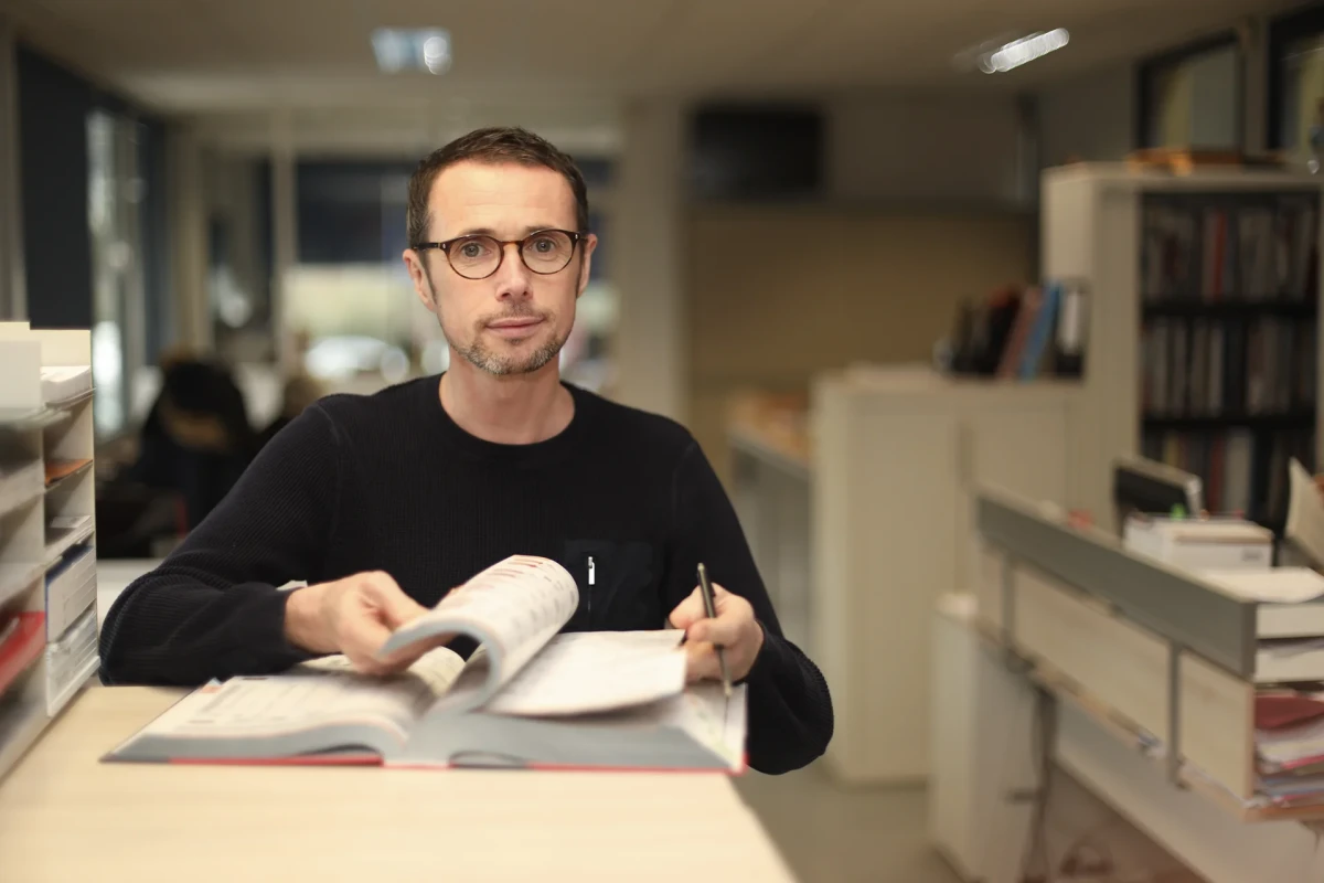 Un collaborateur de Belmet feuillette un catalogue technique dans un bureau moderne, représentant l’expertise, la précision et le conseil apportés aux clients industriels.