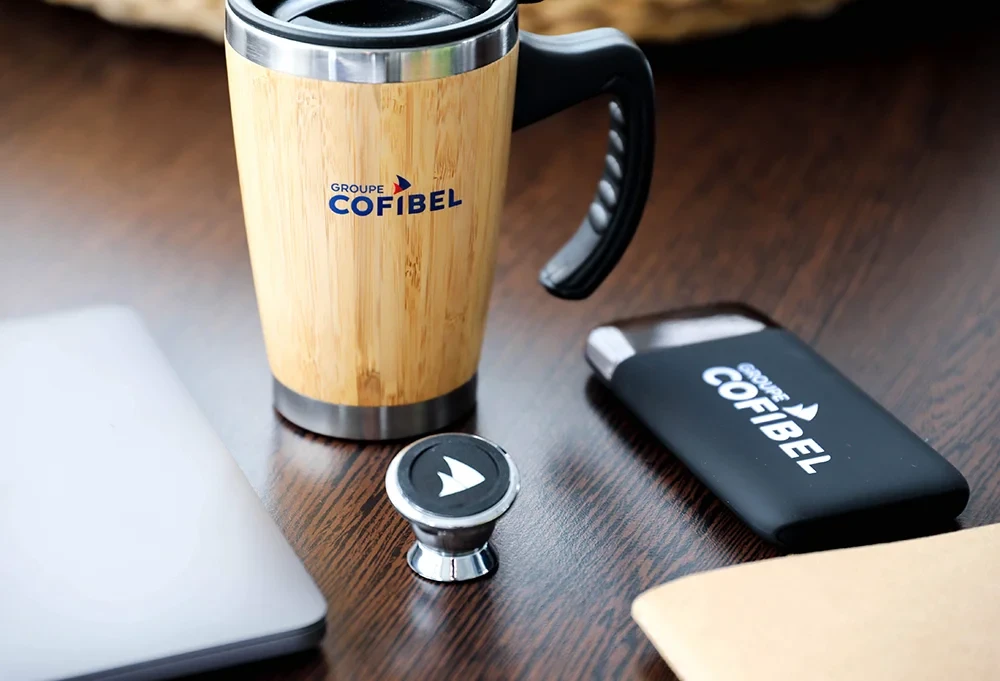 Gourde, clé USB et tampon personnalisés au logo du groupe Cofibel, représentant la déclinaison de l’identité visuelle sur les objets de communication.