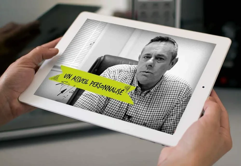 Vidéo d’un intervenant du groupe scolaire Les 2 Rives affichée sur une tablette, avec l’accroche « Un accueil personnalisé »