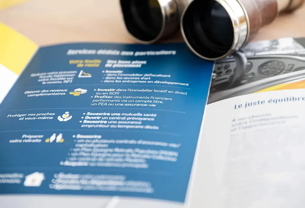 Gros plan sur une double page de la plaquette Océanic Finance. On distingue des icônes illustrant des services liés à la fiscalité, à l’épargne, à la protection et à la retraite, imprimés en blanc et jaune sur fond bleu marine.