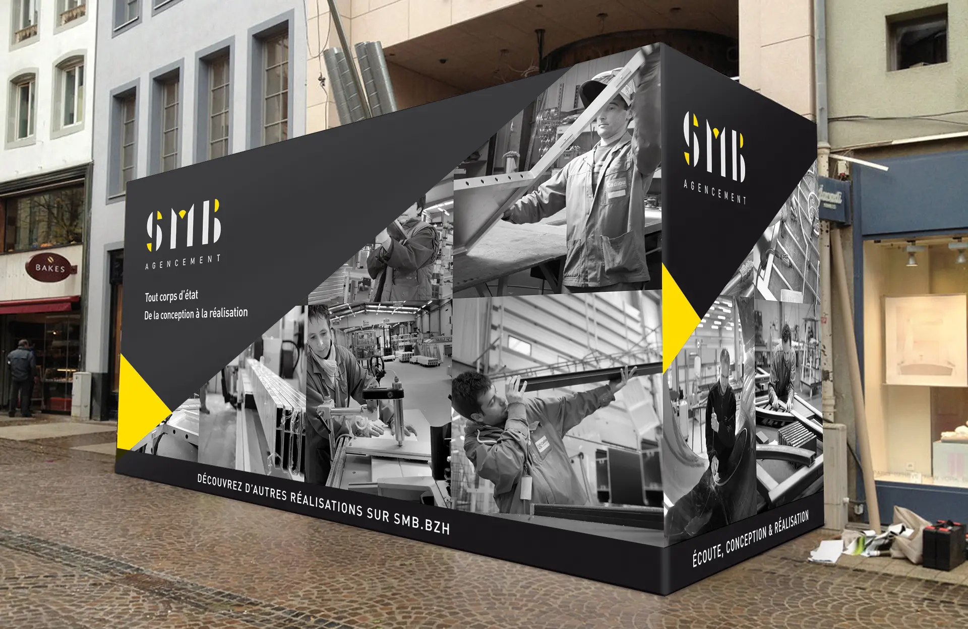 Habillage noir et jaune sur palissade de chantier, illustrant les savoir-faire de SMB Agencement avec le nouveau logo