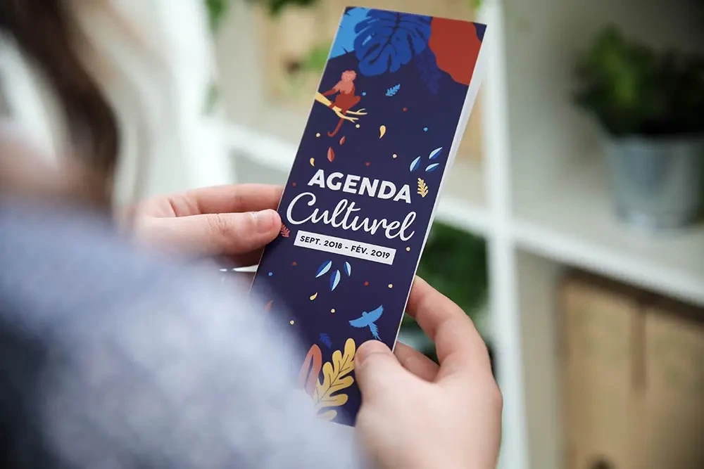 Vue rapprochée d’un habitant tenant le guide culturel de Plouzané dans ses mains, conçu par l’agence Hippocampe avec une charte graphique poétique