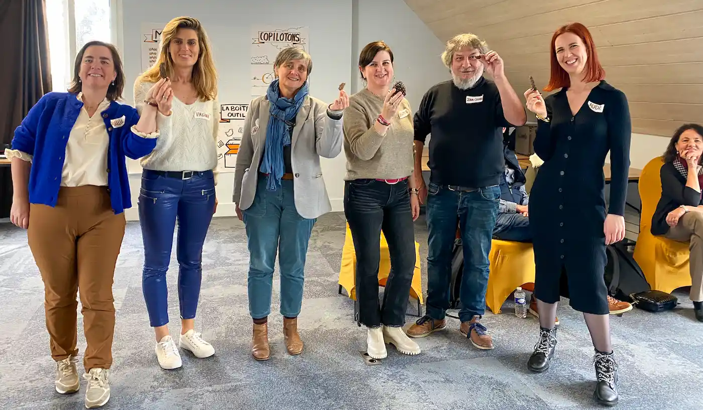 Six participants debout présentant leurs objets symboliques – exercice d’expression et de représentation des valeurs individuelles au sein du CACT.