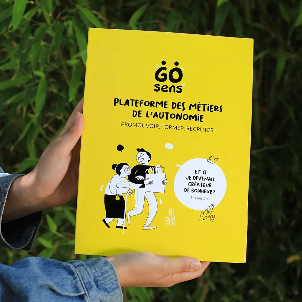 Vue frontale d’une chemise cartonnée jaune vif marquée « GoSens - Plateforme des métiers de l’autonomie », illustrée de personnages souriants et du message : « Et si je devenais créateur de bonheur ? ».