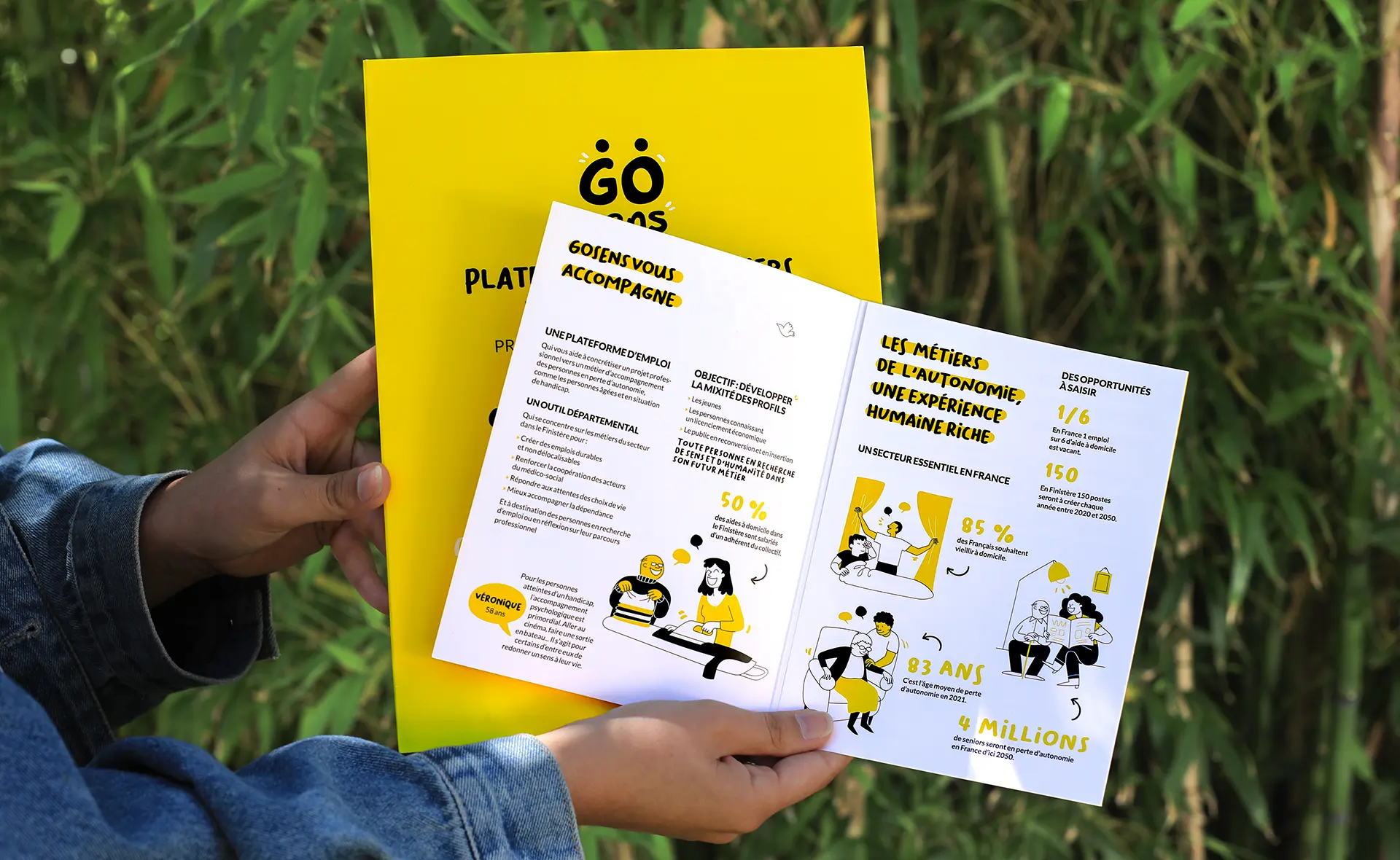 Deux mains tiennent une brochure de la plateforme GoSens, présentant des données et illustrations sur les métiers de l’autonomie, avec un fond vert végétal en arrière-plan.